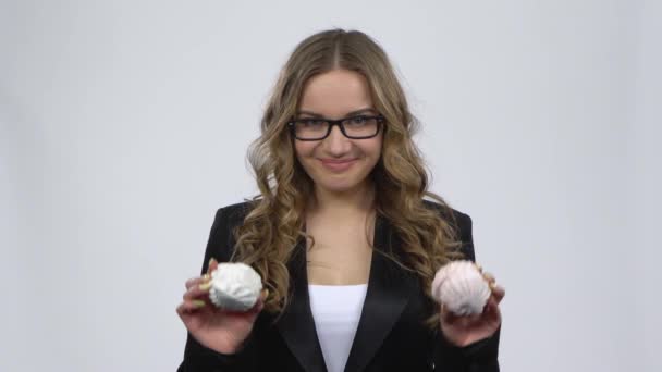 Obsitated kvinna som håller två marshamallow och vill äta den på grå bakgrund — Stockvideo