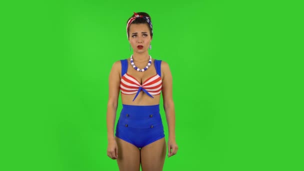 Beautiful girl in a swimsuit in anticipation of worries, then guilty hides her eyes. Green screen — Stock Video