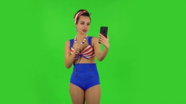 Mayolu güzel bir kız cep telefonuyla selfie çekiyor sonra da fotoğraflara bakıyor. Yeşil Ekran