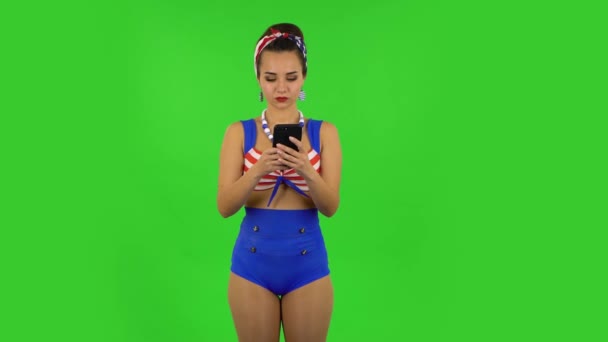 Mooi meisje in een badpak sms 't op haar telefoon en verheugt zich. Groen scherm — Stockvideo