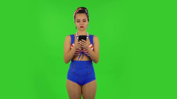 Hermosa chica en un traje de baño es enojado mensajes de texto en su teléfono. Pantalla verde — Vídeos de Stock