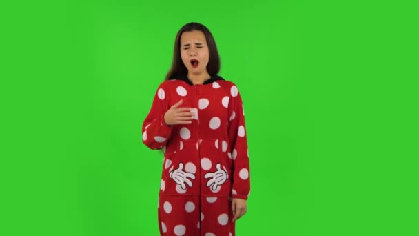 赤いフリースのパジャマの美しい女の子は、就寝時のコンセプトをあくびをしています。緑の画面 — ストック動画