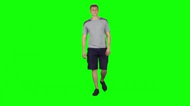 Genç adam yürüyor ve gülümsüyor, yeşil ekranda harikalar yaratıyor, Chroma Key