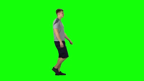 緑の画面を歩いている若い男。プロフィール側表示 — ストック動画