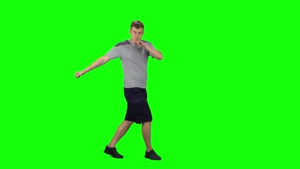 Le gars va danser, sourit et se réjouit sur un écran vert.Profil vue de côté 