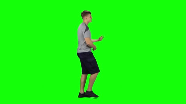 Guy va y baila, sonríe y se regocija en una pantalla verde.Vista lateral del perfil — Vídeos de Stock