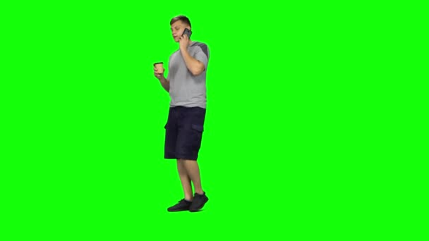 Young male walking talking on the phone and drinking coffee. Chroma Key — Stock Video