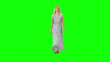 Uzun gri elbiseli sarışın kız yeşil ekrana doğru kameraya doğru bakıyor. Yavaş çekim