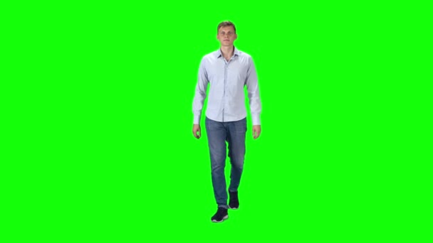 Mladík v šedé košili, džínách a teniskách na zeleném pozadí. Zpomalený pohyb. — Stock video