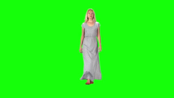 Fille blonde dans une longue robe grise va et regarde directement dans la caméra contre un écran vert. Mouvement lent — Video