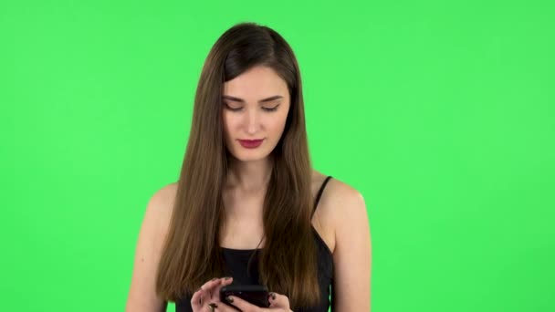 若い笑顔の女性は彼女の電話でテキストメッセージ。緑の画面 — ストック動画