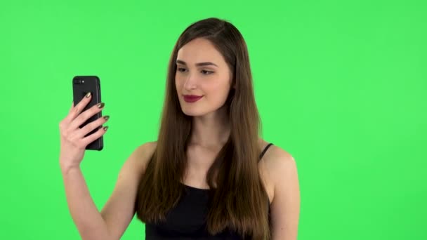 Smiling girl talking for video chat using mobile phone and rejoice on green screen — Stock Video