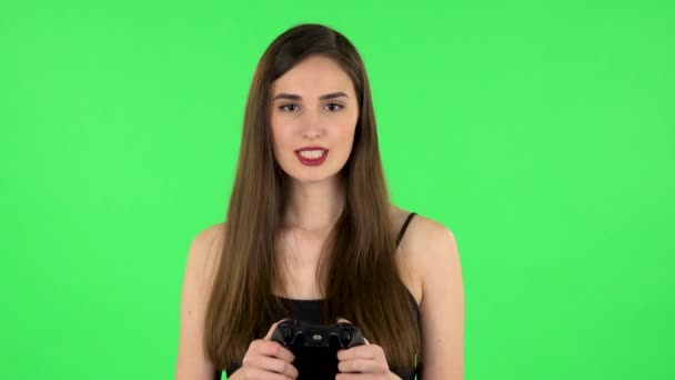 Lány játszik egy videojáték segítségével vezeték nélküli vezérlő örömmel és örömmel. Zöld képernyő — Stock videók