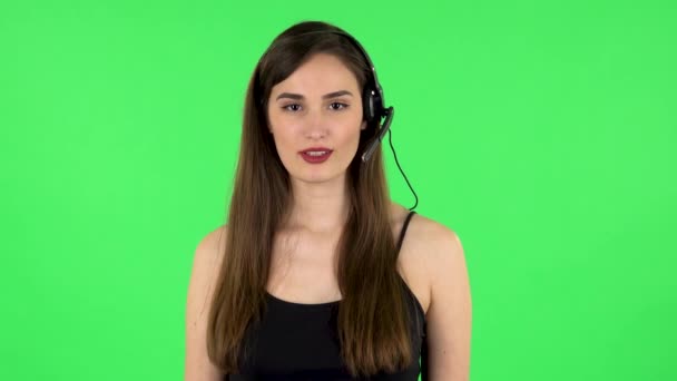 En ung pige, der taler i høretelefoner. Grøn skærm – Stock-video