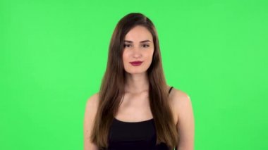 Kadın ayakta duruyor, gülümseyerek yayılıyor ve kameraya bakıyor. Yeşil Ekran