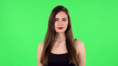 Kadın ayakta duruyor, gülümseyerek yayılıyor ve kameraya bakıyor. Yeşil Ekran