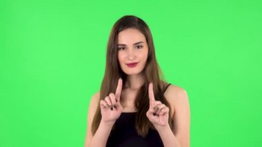 Sevimli kız gülümser, parmaklarıyla kalbini gösterir ve öpüşür. Yeşil Ekran