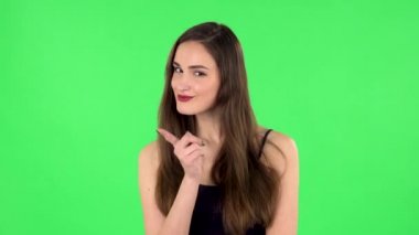 Kız dikkatlice dinliyor, parmağıyla tehdit ediyor ve başını baştan çıkarıcı bir şekilde sallıyor. Yeşil Ekran
