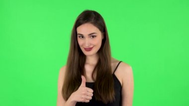 Genç, neşeli bir kadın baş parmağını kaldırıyor. Yeşil Ekran