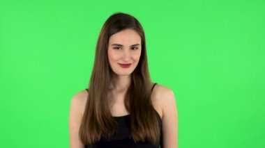 Sevimli kız geniş bir şekilde gülümsüyor ve flört ediyor. Yeşil Ekran