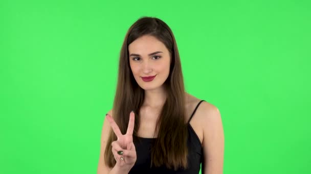 Dívka ukazuje dvouprsté vítězné gesto. Zelená obrazovka — Stock video