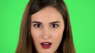 Beautiful brunette woman looks at the camera and surprises. Close up. Green screen