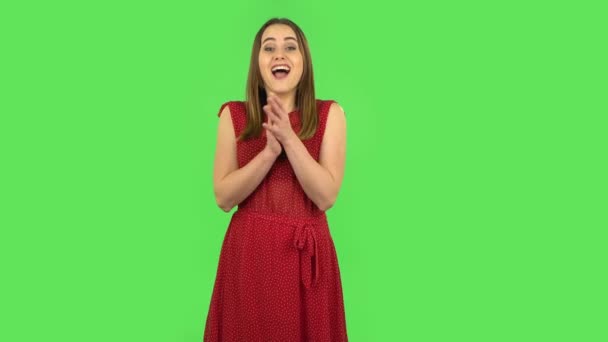 Chica tierna en vestido rojo está aplaudiendo sus manos con wow alegría feliz y deleite. Pantalla verde — Vídeo de stock
