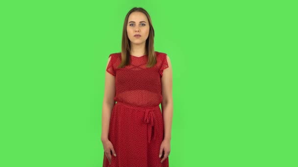 Tender girl in red dress is talking about something then making a hush gesture, secret. Green screen — Stockvideo