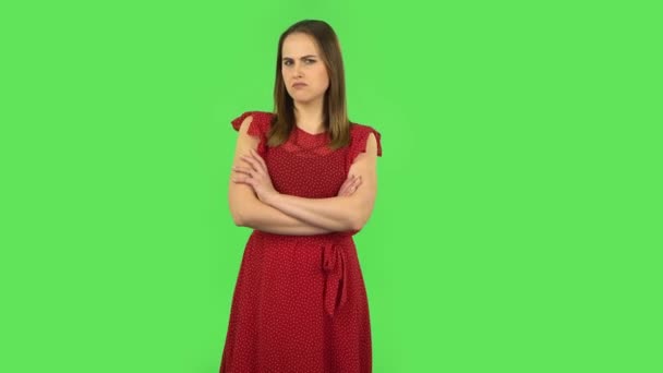 Tender girl in red dress is standing offended and then smiling. Green screen — Stockvideo