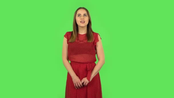 Tender girl in red dress is daydreaming and smiling looking up. Green screen — Wideo stockowe