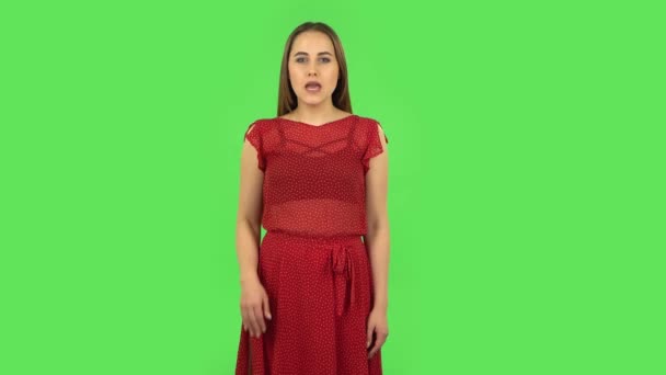 Нежная девушка в красном платье кричит кому-то. Зеленый экран — стоковое видео