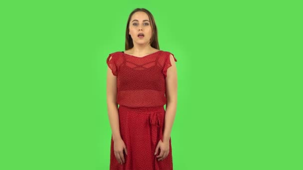 Een teder meisje in rode jurk in afwachting van zorgen, dan glimlachend en trots op zichzelf. Groen scherm — Stockvideo
