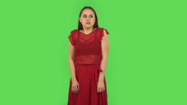 Tender girl in red dress girl froze and trying to keep warm. Green screen