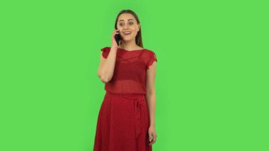 Tender girl in red dress is talking for mobile and shocked then dissatisfied. Green screen