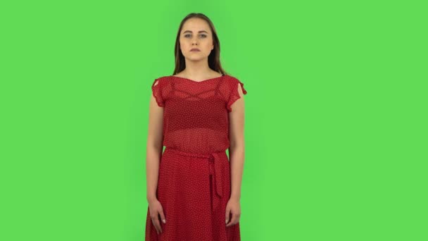 Tender girl in red dress is frightened then sighs with relief and smiles. Green screen — Stock Video