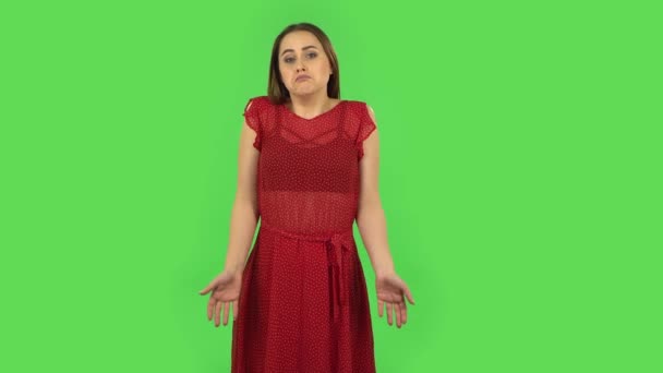 Tender upset girl in red dress is shrugging and sighing. Green screen — Stock Video