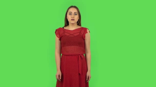Нежная девушка в красном платье расстроена и вздыхает. Зеленый экран — стоковое видео