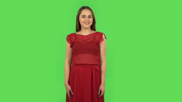 Tender girl in red dress is smiling broadly and winking. Green screen — Stock Video