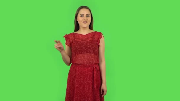 Tender girl in red dress is showing two fingers victory gesture. Green screen — Stock Video