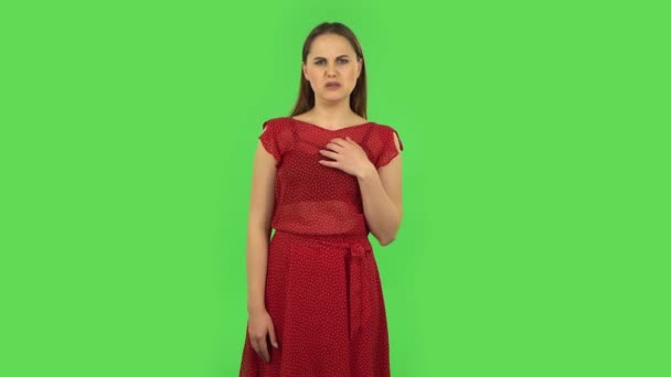 Tender girl in red dress is showing disgust for bad smell or taste. Green screen — Stock Video