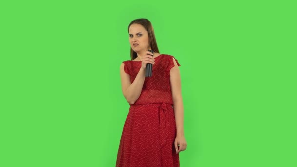 Chica tierna en vestido rojo con televisor remoto en la mano, encendiendo la televisión. Pantalla verde — Vídeos de Stock