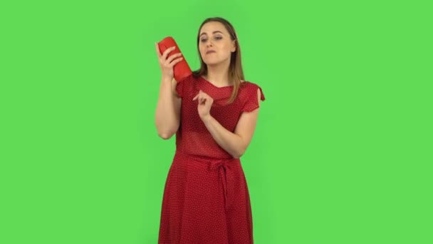 Tender girl in red dress is listening to music with bluetooth portable speaker and dancing. Green screen — 图库视频影像