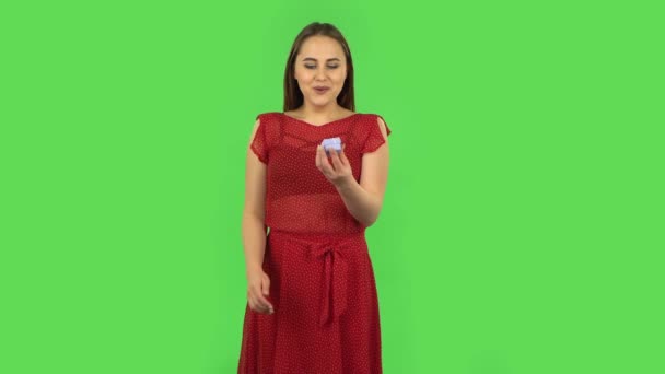 Tender girl in red dress is opening a small box with a surprise and is very rejoicing, saying yes. Green screen — ストック動画