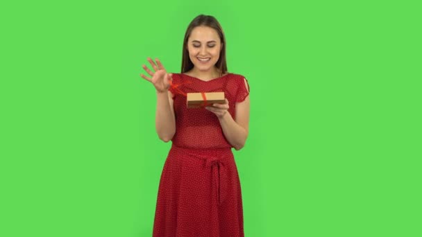 Tender girl in red dress is opening the gift, very surprised and rejoicing. Green screen — Αρχείο Βίντεο