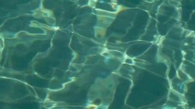 Turquoise sea with clear water, sand and small fish are visible at the bottom. Slow motion. Close up