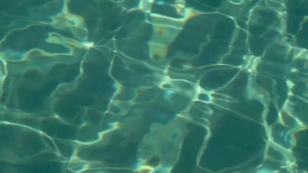 Mar turquesa con agua clara, arena y peces pequeños son visibles en el fondo. En cámara lenta. De cerca. — Vídeos de Stock