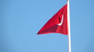 Close-up view flag of Turkey waving in the wind on a blue sky background without clouds
