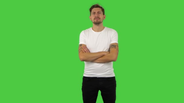 Confident guy is looking straight, crossing his arms over his chest and nodding his head. Green screen — Stock Video