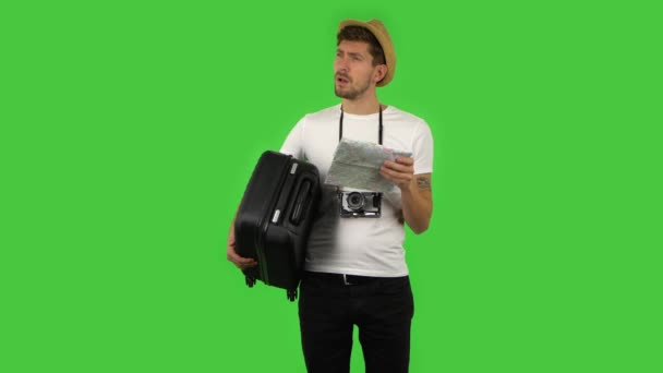 Tourist mit Koffer in der Hand und Retro-Kamera begutachtet sorgfältig die Landkarte, dann die Sehenswürdigkeiten. Grüner Bildschirm — Stockvideo