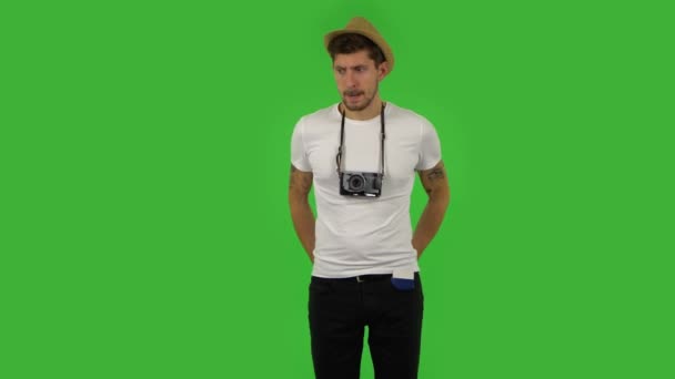 Tourist in a hat with a retro camera and a passport in his pocket searches for money and finds a credit card. Green screen — Stock Video